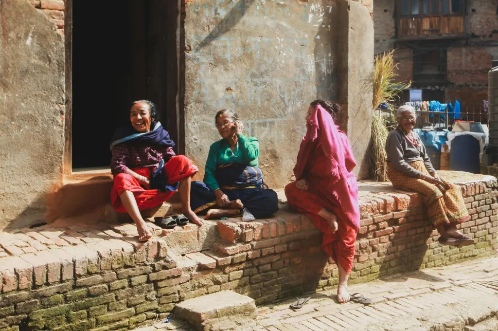 women sitting in front of a house on a raised brick platform--palliative care