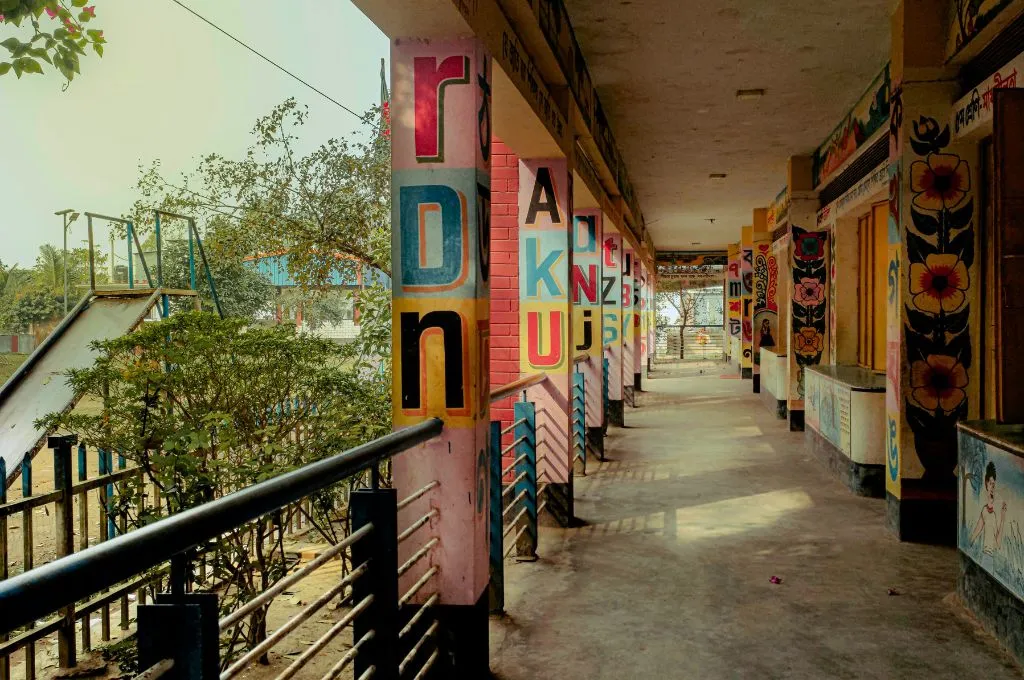 an empty school corridor with letters of the alphabet and colourful drawings painted on the walls and pillars--inclusion