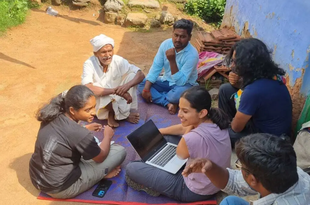 a group of people, on of whom is carrying a laptop, sitting on the floor and talking--conservationists