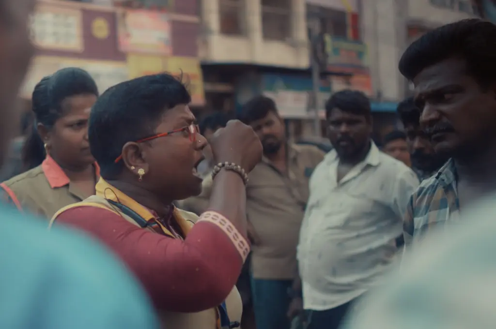 a woman facing a man while addressing a large crowd with one of her hands raised--women auto drivers
