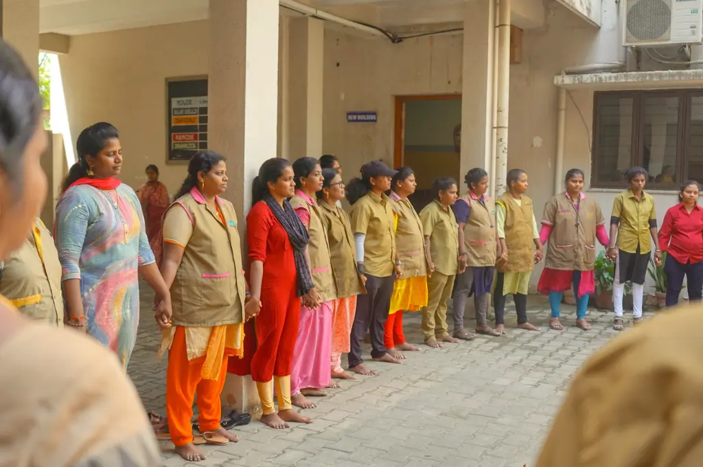 a group of women, some of whom are wearing khakee jackets, standing in a circle in front of a yellow building--women auto drivers