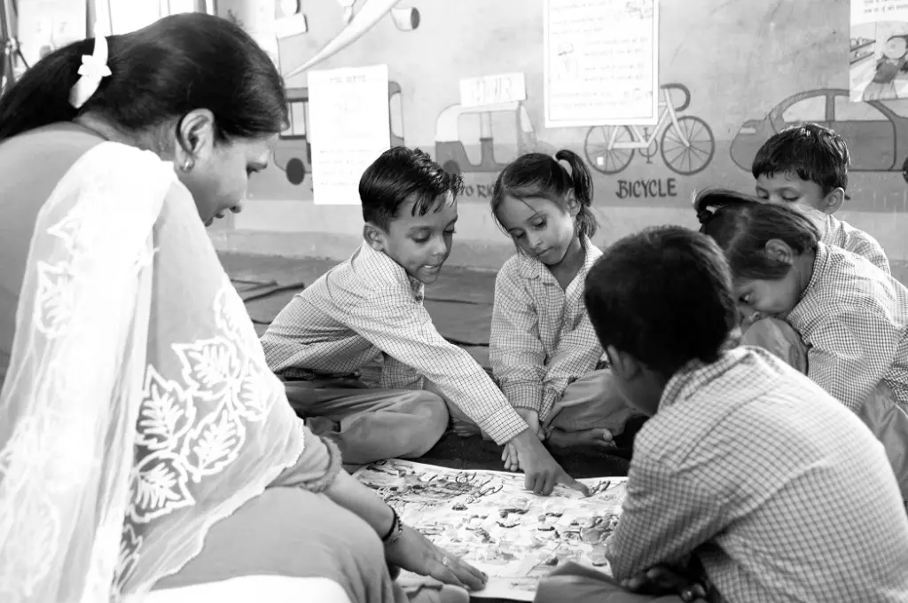 a black-and-white image of a teacher sitting on the floor with her students--foundational learning