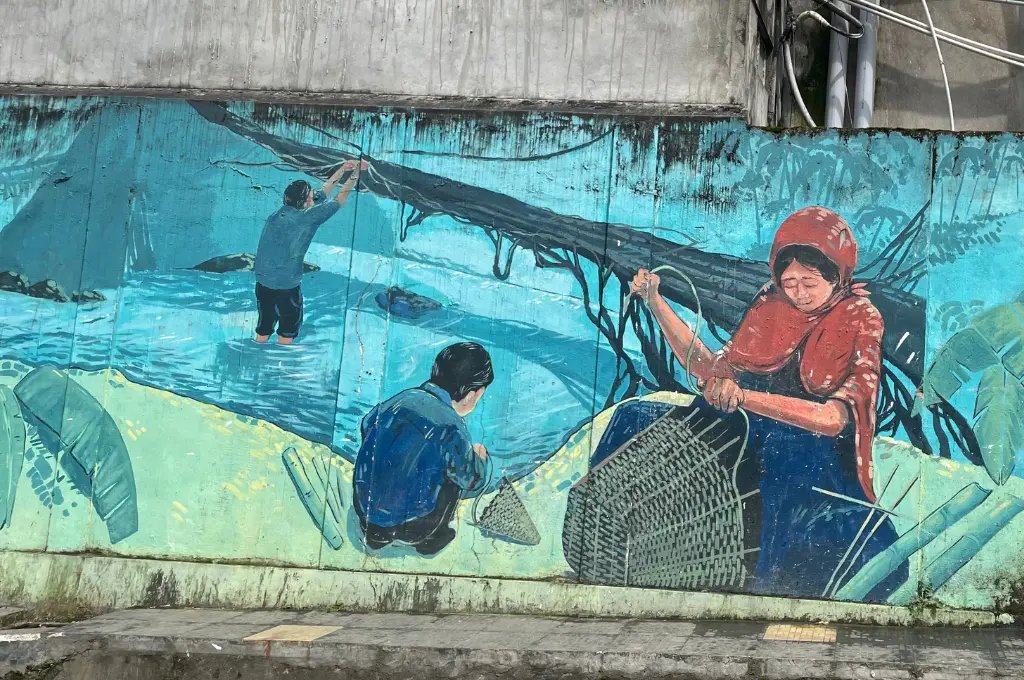 a mural of a woman weaving a basket by the riverside and two children playing--Mizoram nonprofit