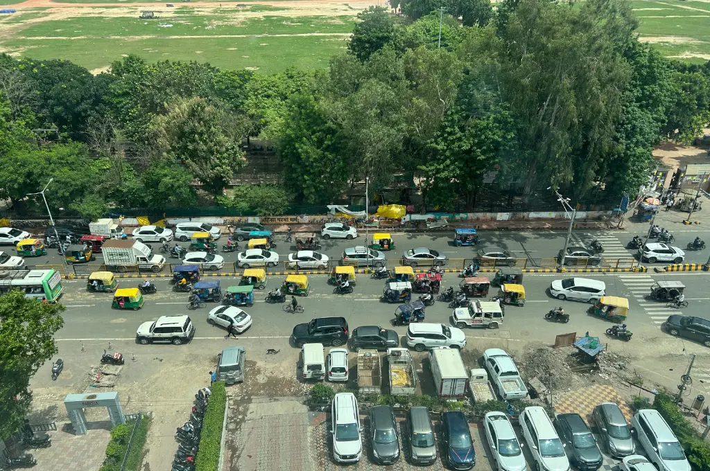 a parking lot adjacent to a field with a row of trees acting as a border between the two--urban mobility
