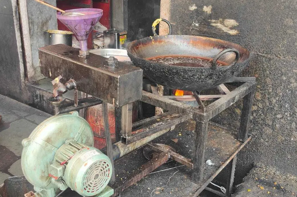 a customised furnace for cooking that runs on diesel and machine oil, on top of which is a large wok containing cooking oil--LPG crisis