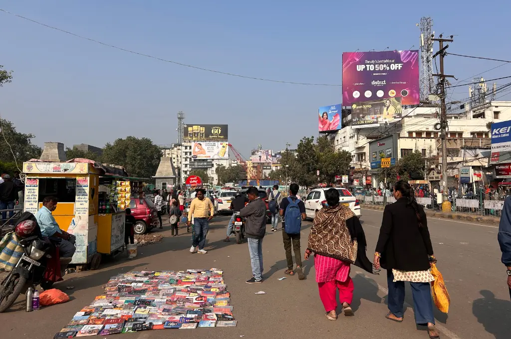 busy street with pedestrians, cars, motorcycles, and roadside vendors selling books and eatables--urban mobility