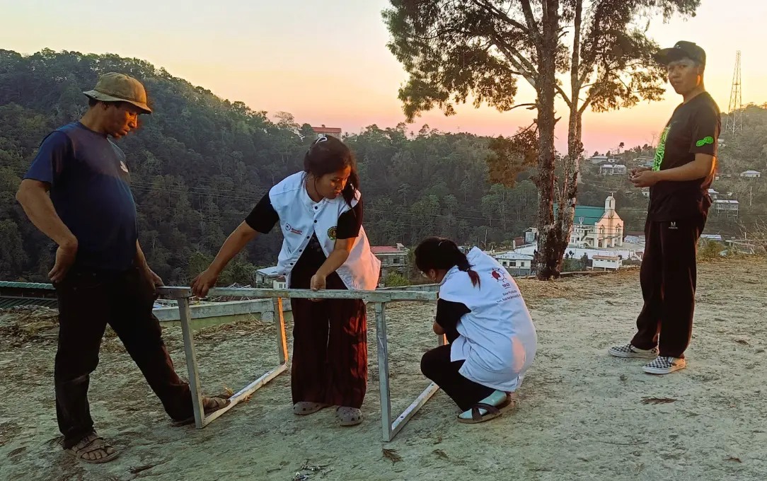 a group of four people attempting to assemble a structure of some sort--Northeast India
