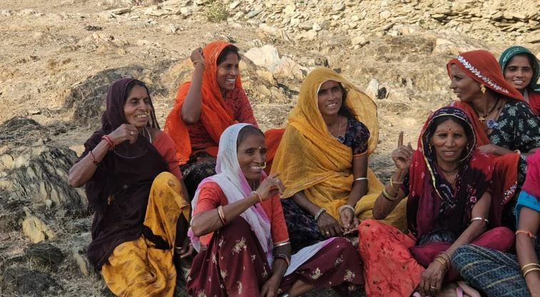 a group of women sitting in the shade smiling and talking--MGNREGA