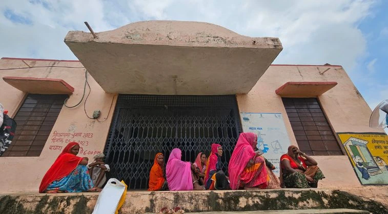 a group of women sitting on a raised platform outside the entrance to a building--MGNREGA