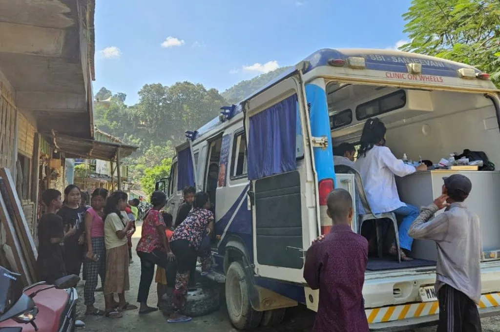 a mobile medical van with healthcare professionals inside and patients queued up outside--healthcare