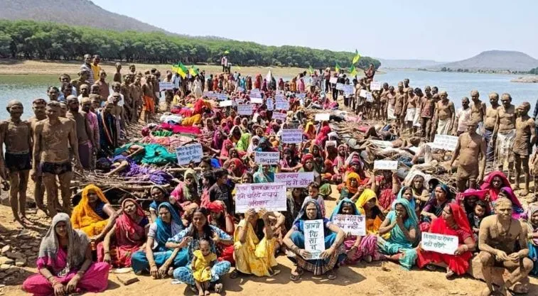 A large group of people, predominantly women, with most sitting on the ground and a few people standing around them, protesting against the Ken-Betwa Link project in 2026--Ken-Betwa protest