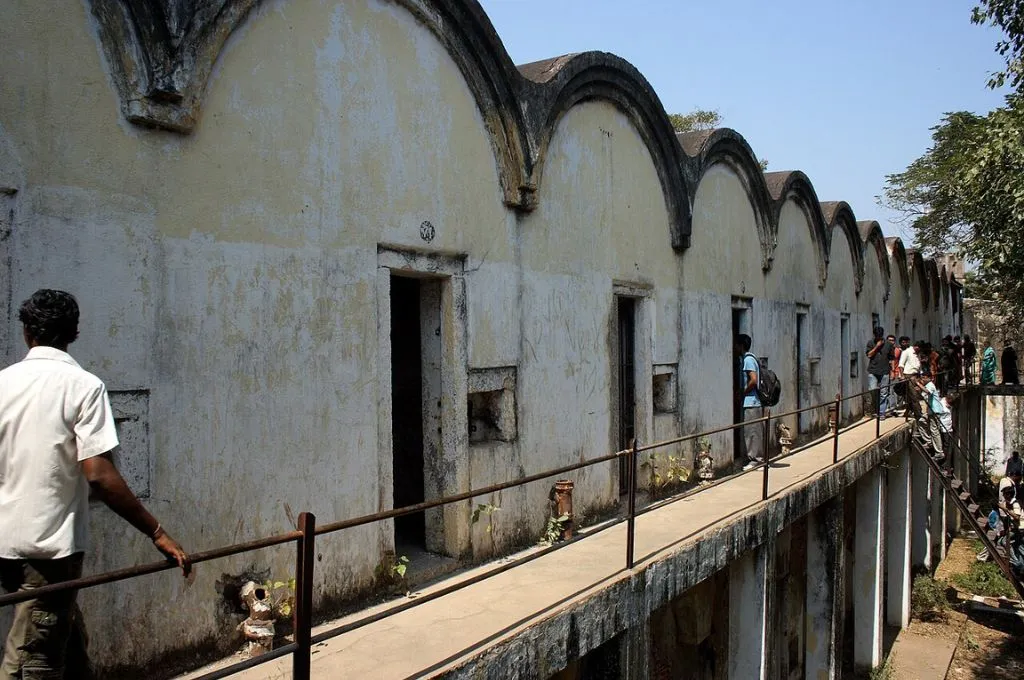 People queued up on a staircase leading up to an open corridor with multiple doors in a slightly run-down building--prison reform India