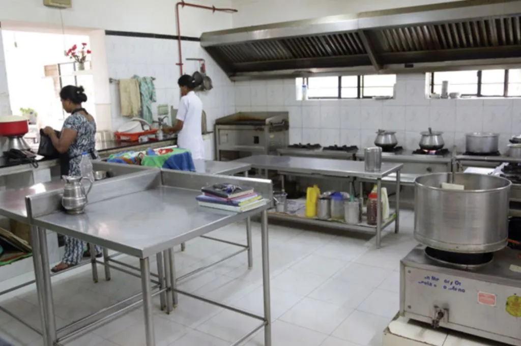two women working in a large kitchen with silver steel tables--hospice facilities