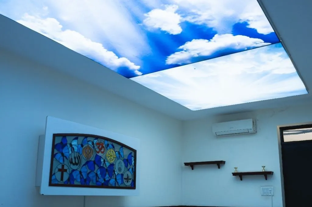 a multi-faith prayer room with a mural on a wall bearing symbols of several religions, including Christianity, Islam, Sikhism, Hinduism, Buddhism, Jainism--hospice facilities