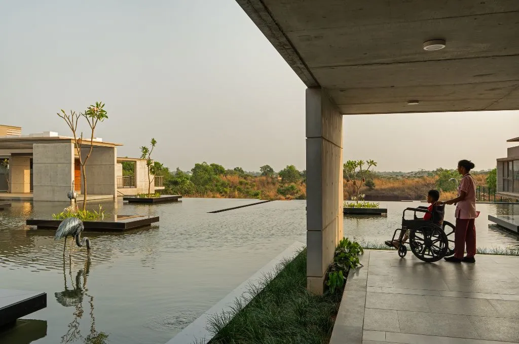 a person in a wheelchair being steered by a healthcare worker looks on at an artificial pond--Hospice care