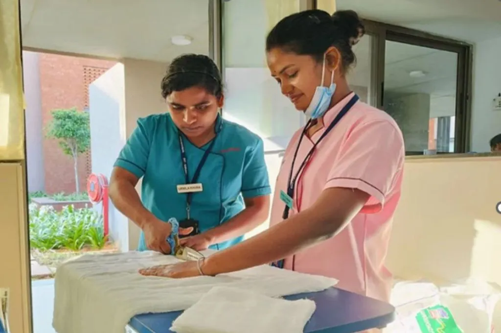two female nurses cutting white fabric on a blue table--hospice facilities