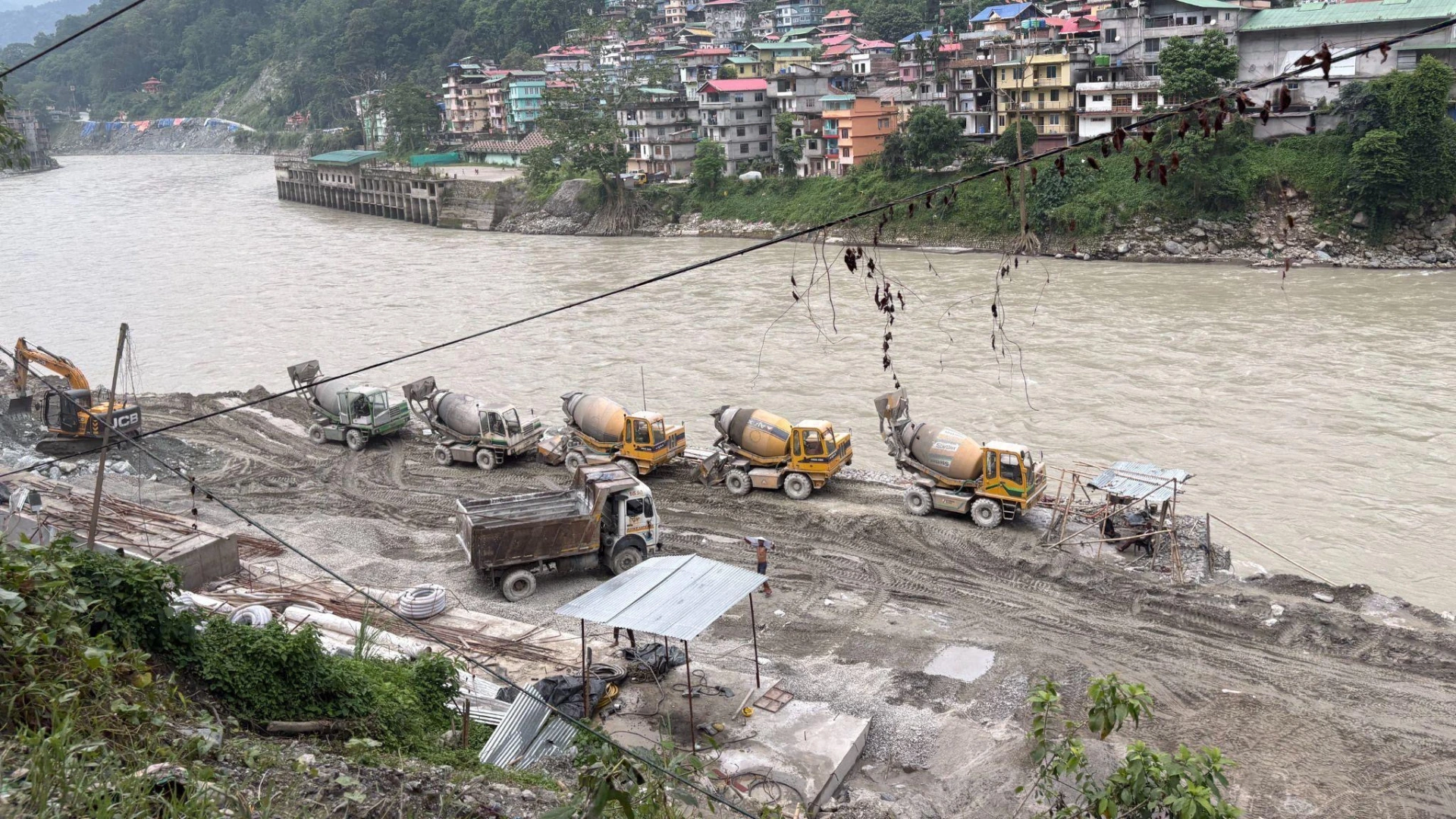 concrete mixers parked on a river bank that has been flattened and prepared for construction--Teesta hydropower projects