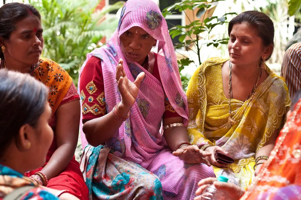 a woman in a pink saree addressing other women sitting around her in a circle--primary healthcare