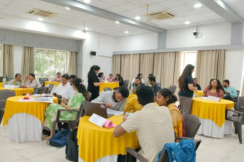 people seated around circular tables in a brightly lit hall--organisational development