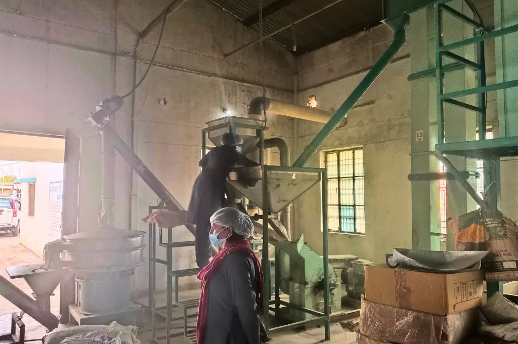 two women wearing hairnets and masks operating machinery in a Take Home Ration plant--take home ration
