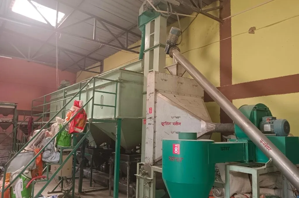 close-up short of a machine at a Take Home Ration plant, with different parts of the machinery ("converyor", "cooling machine") labelled in Devnagri--ICDS scheme
