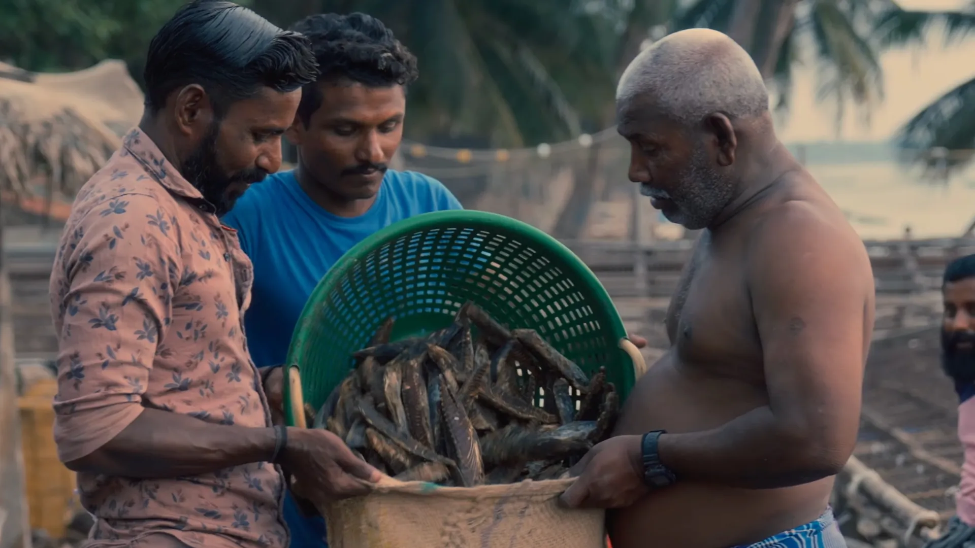three men transferring fish from a plastic basket into a sack--community engagement in Lakshadweep