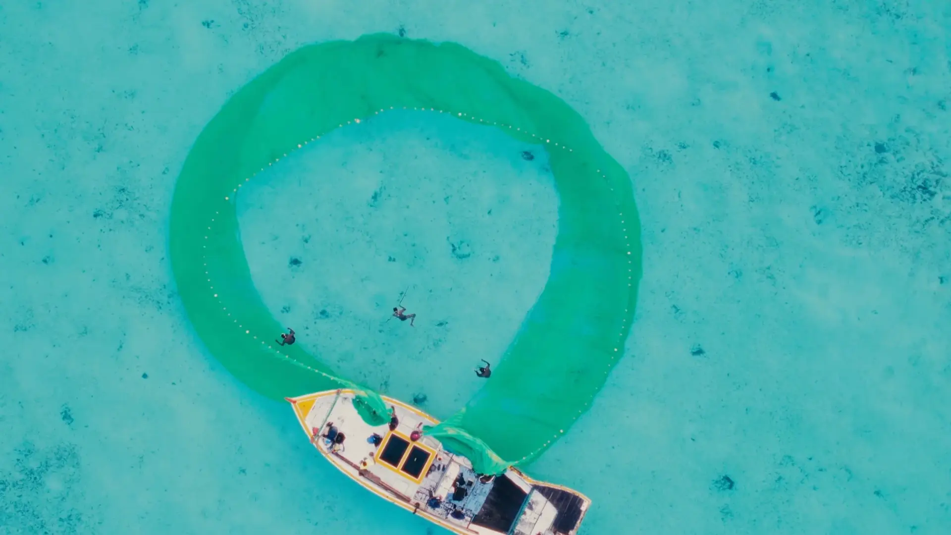 an aerial view of a boat and three divers in the sea--community engagement in Lakshadweep
