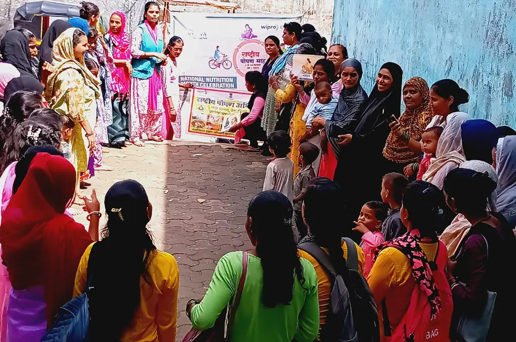 a large group of women attend a meeting on the street. in the background are some posters and banners--Social return on investment