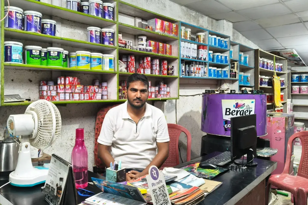 a man sitting behind the counter of a wall paint supply store--SIR