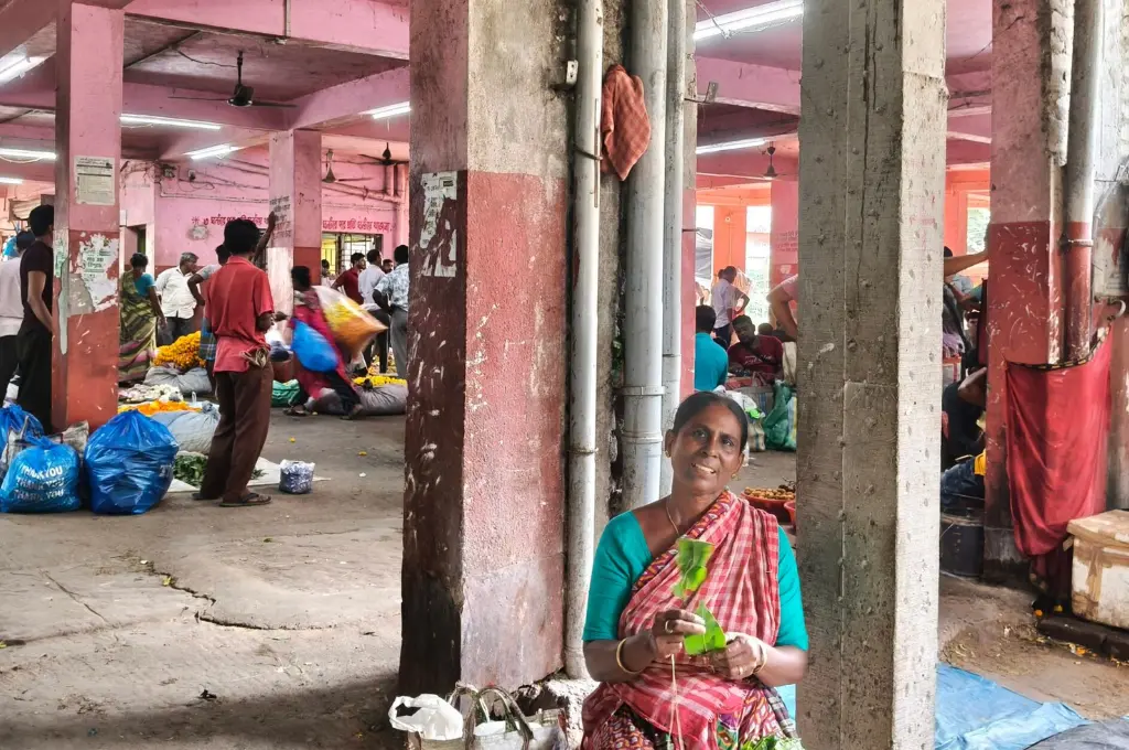 a woman threading leavessitting next to a pillar in a large hall