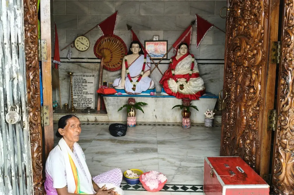 a woman clad in white sitting at the threshold of a temple with two statues--SIR