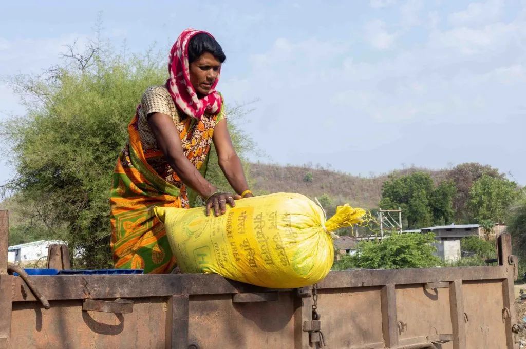 a woman standing in a trolley handling a bright yellow fertiliser sack--fertilisers