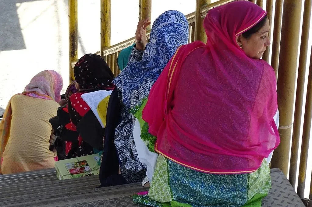 four women sitting on a staircase, each on one step, with their backs to the camera--SEHAT
