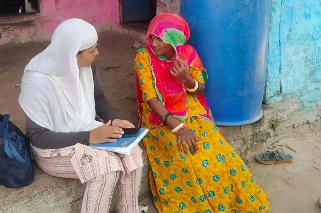 two women sitting and talking. one of them is holding a smartphone and has a notebook on her lap_SIR deletion